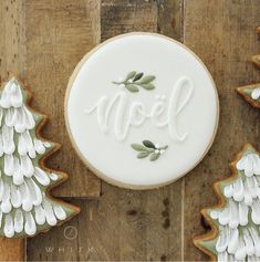 decorated cookies with the word noel written in white frosting next to christmas trees on wooden boards