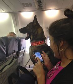 a woman holding a dog in her lap while looking at the screen on an airplane