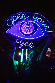 a neon sign with the words eyes on it in front of a woman's face