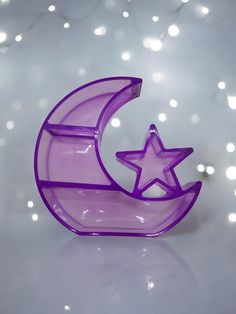 a purple glass object with a star and moon in the middle on a white surface