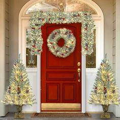 a red door decorated with christmas wreaths and pine cones