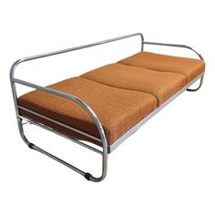 a metal frame couch with an orange cushion on it's back and seat pad