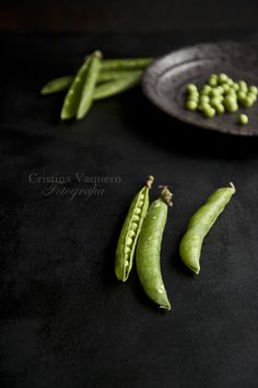 green beans and pea pods on a black surface with a plate in the foreground