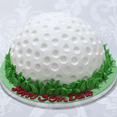 a golf ball cake is decorated with green grass and red berries on the bottom layer