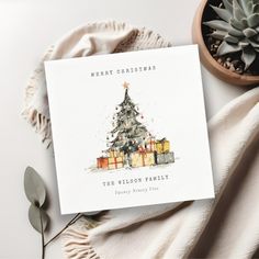 a christmas card sitting on top of a table next to a potted cactus plant