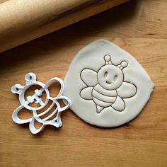 two cookie cutters sitting next to each other on a wooden table with an image of a bee