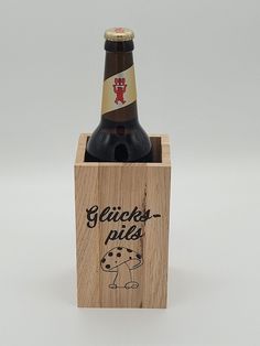 a wooden box with a bottle in it and a drawing on the lid that says geries - pils