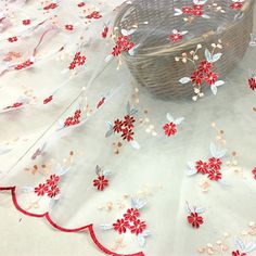 a basket sitting on top of a table covered in red and white fabric with flowers