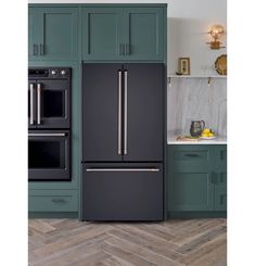 a black refrigerator freezer sitting inside of a kitchen next to green cabinets and drawers