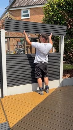 a man standing on the side of a house holding onto a wall with his hands