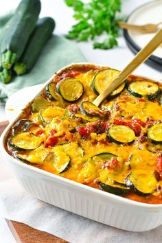 a casserole dish with zucchini, cheese and sauce in it on a table