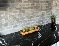 a black marble counter top with a wooden bowl filled with broccoli on it