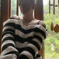 a woman standing in front of a window wearing a black and white striped sweater