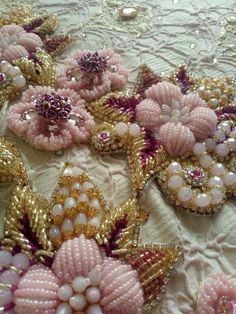 some pink and gold brooches are laying on a white table cloth with lace