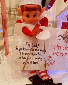 an elf holding a sign in front of a store window