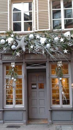 a store front decorated for christmas with silver and white decorations on the door, along with snowflakes hanging from the windows