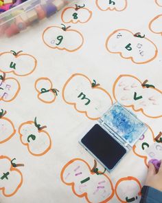 a child's hand is writing numbers on a tablecloth with apples and pumpkins