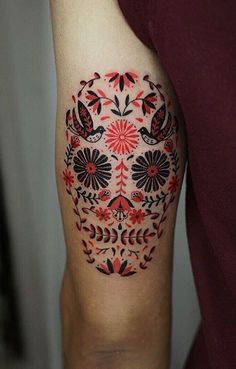 a person with a red and black sugar skull tattoo on their arm