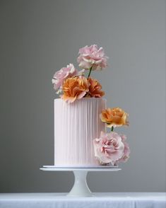 a three layer cake with pink icing and flowers on top