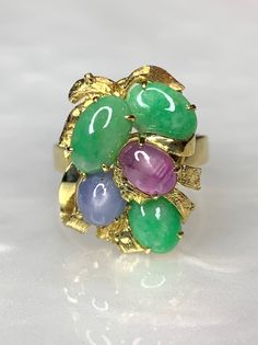 Jade Ring, Jade Rings For Women, Jade Ring Gold, Vintage Gemstone Ring, Star Sapphire Ring, Cabochon Ring, Bouquet Ring, Multi Stone Ring A multi colored gemstone bouquet ring with solid 14k gold leaf/ petal detailing. Featuring 3 oval shaped genuine green jade stones along with a single round star sapphire and a single oval star ruby. *Approximate ring weight: 6.36 grams *Ring size: US 7 1/2 * Complimentary resizing is available up to 3 sizes larger or smaller than stated size. Multicolor Cabochon Rings Fine Jewelry, Multicolor Cabochon Rings In Fine Jewelry Style, Heirloom Multi-stone Oval Cabochon Rings, Multicolor Cabochon Rings For Anniversary, Green Multi-stone Oval Cabochon Jewelry, Jade Rings For Women, Ring Bouquet, Bouquet Ring, Antique Emerald Ring