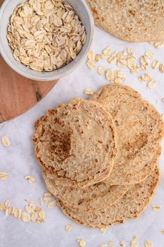 a stack of flat bread next to a bowl of oatmeal