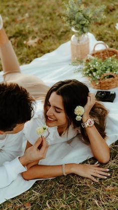 a man and woman laying on the ground with flowers in their hair smiling at each other