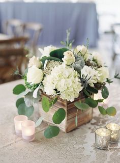 white flowers and greenery in a wooden box on a table