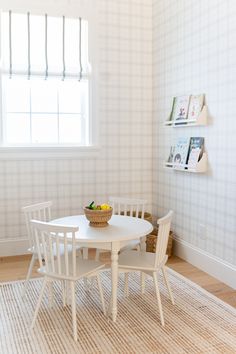 a white table and chairs in a room with a rug on the floor next to it