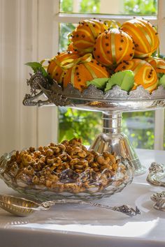 an assortment of fruits and nuts on a silver platter next to a glass window