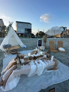 a table set up on the beach with candles and decorations for an outdoor dinner party