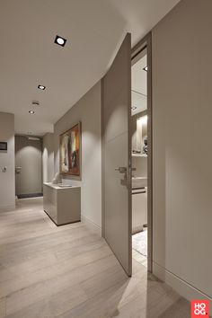 an empty hallway with white walls and wood flooring is seen in this image from the entrance to the bathroom