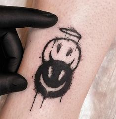 a black and white photo of a smiley face on someone's arm with ink splatters all over it