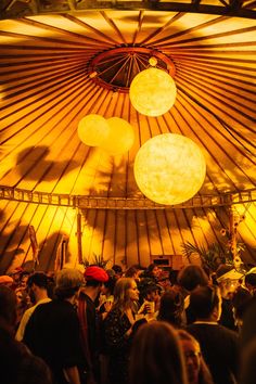 a group of people standing under a large tent with lights on it's ceiling