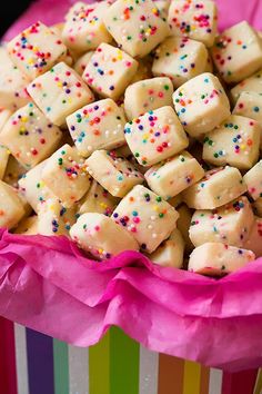 a colorful box filled with lots of white chocolate covered in sprinkles