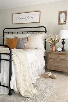 Farmhouse bedroom with a black iron bed and wood nightstand. The bedding is white linen with ruffles and there is a cream knit throw draped over the bed. There are copper touches in the pillows and the florals on the nightstand. Guest Bedroom Inspiration Farmhouse, Farmhouse Bedroom Apartment, Bedspreads Comforters Farmhouse, Black Metal Bed Frame Bedroom Ideas Farmhouse, Farmhouse Inspired Bedroom, Boho Modern Farmhouse Bedroom, Fall Farmhouse Bedroom, Light And Airy Decor, Master Bedrooms Farmhouse