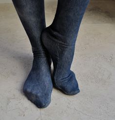 a person standing on the floor with their legs crossed and wearing blue jean pants, black shoes