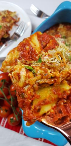 a blue dish filled with lasagna and tomatoes