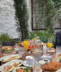 a woman sitting at a table filled with food and drinks in front of an outdoor dining area