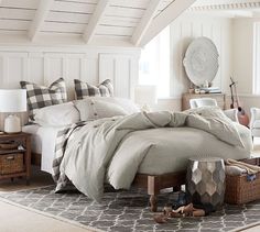 a bedroom with white walls and wood flooring is pictured in this image, the bed has many pillows on it