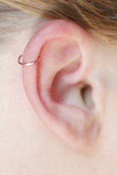 a woman's ear with a thin nose ring