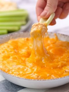 a person is dipping cheese into a casserole dish