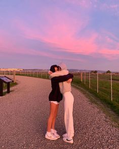 two people hugging each other on a gravel road