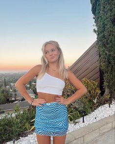 a woman standing in front of a house with her hands on her hips and looking at the camera