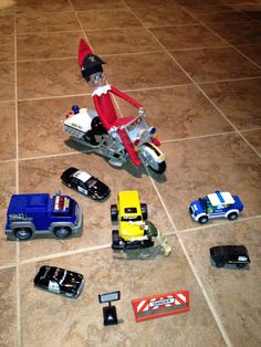 an elf riding on top of a motorcycle next to other toy cars and trucks in the floor