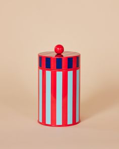 a red, white and blue striped canister with an apple on top sitting in front of a beige background