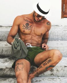 a shirtless man sitting on the steps with his hat and eyeglasses tattooed