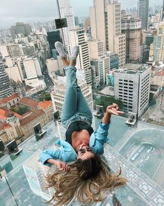 a woman is upside down on the glass floor in a high rise building with cityscape in the background