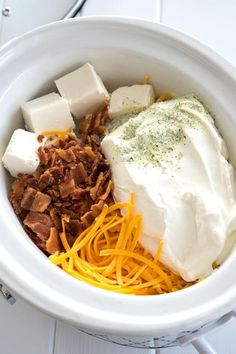 a white bowl filled with cheese, meat and other food on top of a table