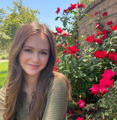 a young woman sitting in front of some flowers