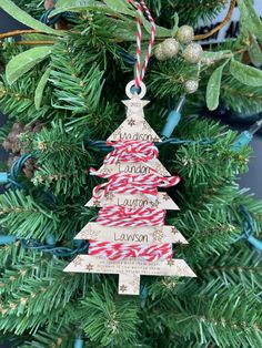 a wooden christmas tree ornament hanging from a pine tree